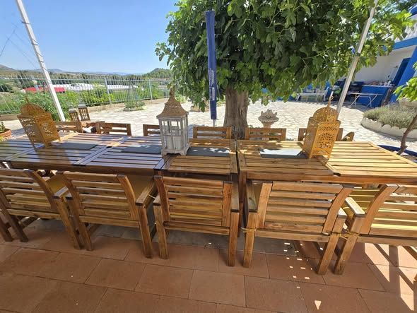 Long wooden dining table for large groups under a tree